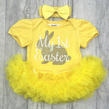 Load image into Gallery viewer, Baby girls short sleeve yellow tutu romper with bow headband above. The tutu romper features a cute gold bunny design with white script style lettering over the top saying My 1st Easter