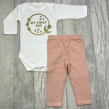 Load image into Gallery viewer, Long sleeve white romper and pink leggings. The romper features gold glitter moon and stars circle design with lettering in the middle saying My First Eid.