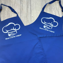 Load image into Gallery viewer, Two Blue Kids Aprons featuring a White Glitter Chef Hat design with Personalised Name in the middle and lettering saying Mum's little helper underneath