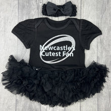 Load image into Gallery viewer, Baby girls short sleeve black tutu romper with bow headband above. The tutu romper features a sparkly silver glitter rugby ball design and white glitter text central over the top saying Newcastle's Cutes Fan.