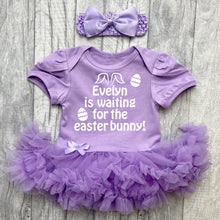 Load image into Gallery viewer, Baby girls short sleeve light purple tutu romper with bow headband above. The tutu romper features white glitter easter eggs design with lettering saying Personalised Name is waiting for the Easter Bunny!