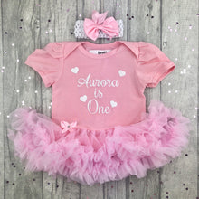 Load image into Gallery viewer, Light pink short sleeve tutu romper with matching bow headband above. The tutu romper features white glitter love hearts design and lettering in the middle saying Personalised Name is One.