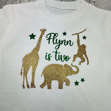 Load image into Gallery viewer, White shirt with gold glitter animals and text 'Flynn is two'.