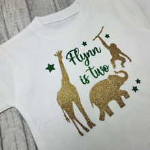 Load image into Gallery viewer, White shirt with gold glitter animals and green text.
