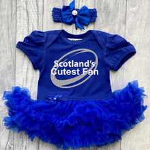Load image into Gallery viewer, Baby girls short sleeve royal blue tutu romper with bow headband above. The tutu romper features a sparkly silver glitter rugby ball design and white glitter text central over the top saying Scotland's Cutes Fan.