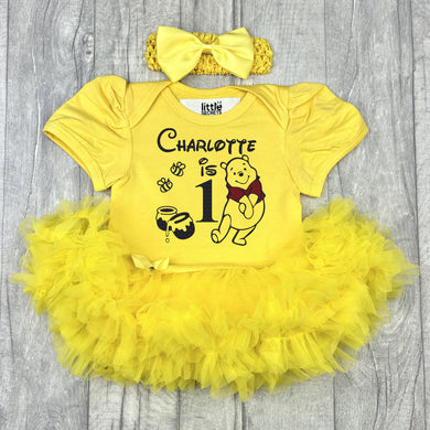 Baby girls short sleeve yellow tutu romper with bow headband above. The tutu romper features a black and red glitter Winnie the Pooh Silhouette, Honey Pots and Bees design with lettering saying Personalised Name is 1.