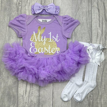 Load image into Gallery viewer, Baby girls short sleeve lilac tutu romper with bow headband above and white socks below. The tutu romper features a gold glitter cute bunny design with white script lettering over the top saying My 1st Easter.
