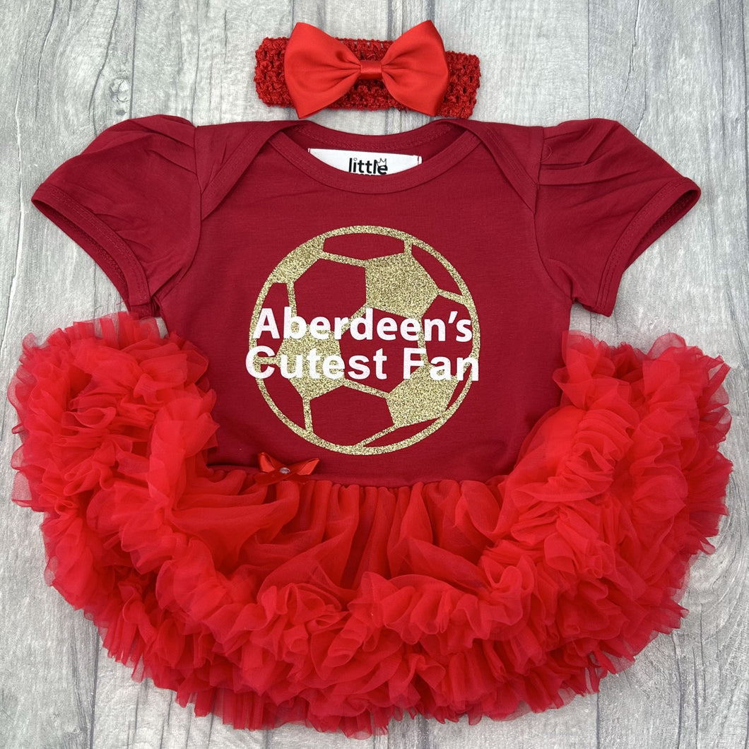 Baby girls red short sleeve tutu romper with bow headband above. The tutu romper features gold glitter football design and white text central over the top saying Aberdeen's Cutest Fan.