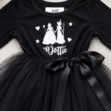 Load image into Gallery viewer, A black long-sleeve toddler dress with a black tulle skirt and a large black ribbon bow at the waist. The bodice has a white graphic print of two princesses, stars, hearts,
