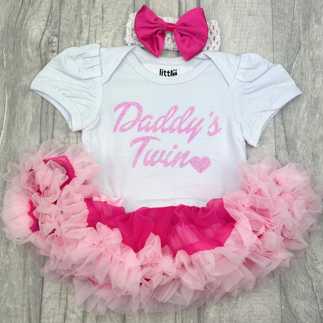 Baby girls short sleeve white and pink tutu romper with bow headband above. The tutu romper features pink glitter lettering saying Daddy's Twin.