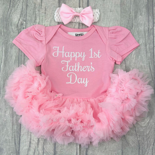 Baby girls short sleeve cotton soft light pink tutu romper with bow headband above. The tutu romper features white glitter script font lettering saying Happy 1st Father's Day. Perfect gift for Daddy.