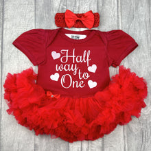 Load image into Gallery viewer, Baby girls red tutu romper with matching bow headband above. The tutu romper features white glitter love hearts design with script lettering saying Half way to One.
