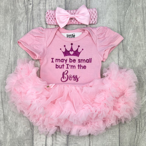 Baby girls light pink short sleeve tutu romper with matching bow headband above, the tutu romper features dark pink glitter princess crown design with lettering underneath saying I may be small but I'm the Boss