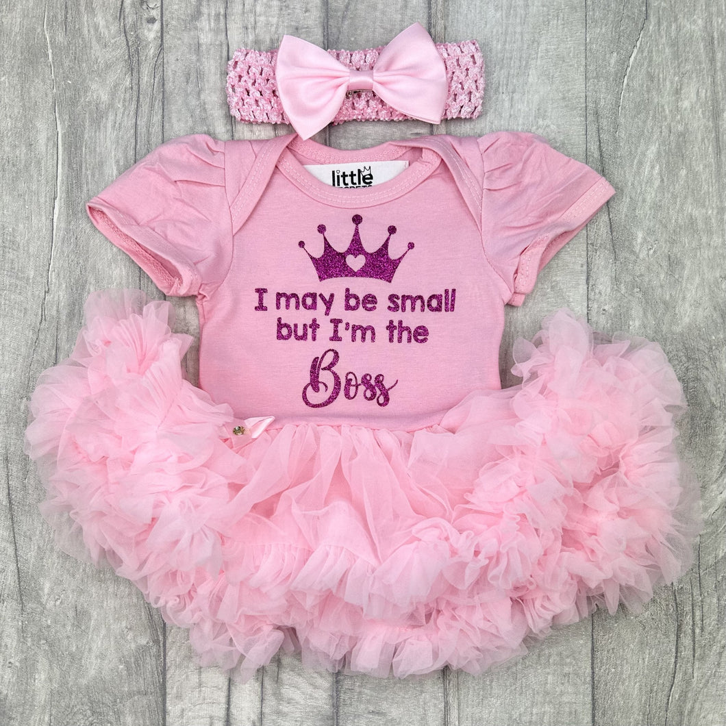 Baby girls light pink short sleeve tutu romper with matching bow headband above, the tutu romper features dark pink glitter princess crown design with lettering underneath saying I may be small but I'm the Boss