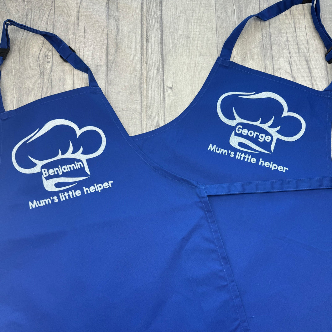 Two Blue Kids Aprons featuring a White Glitter Chef Hat design with Personalised Name in the middle and lettering saying Mum's little helper underneath