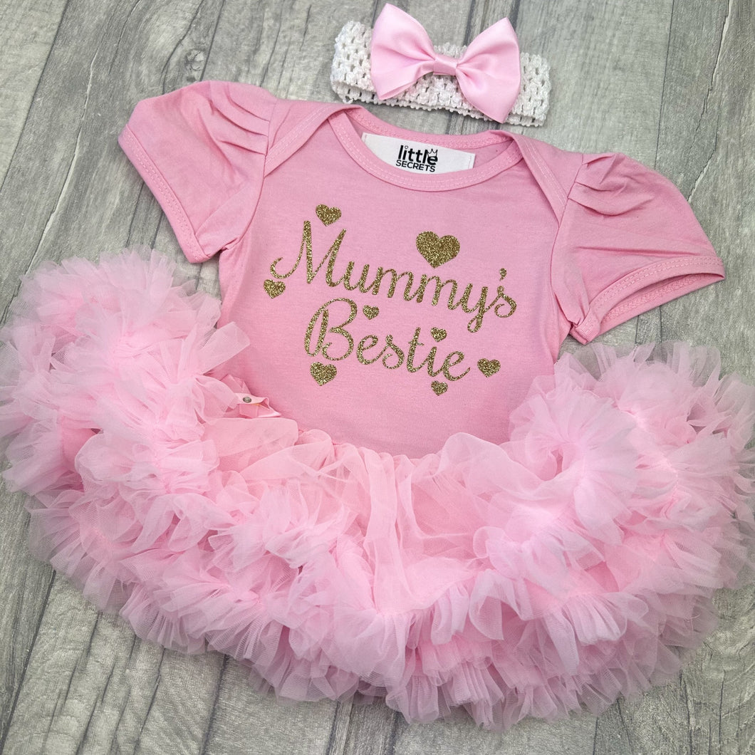 Baby girls short sleeve pink tutu romper with bow headband above. The tutu romper features gold glitter love hearts design with script style text saying Mummy's Bestie.