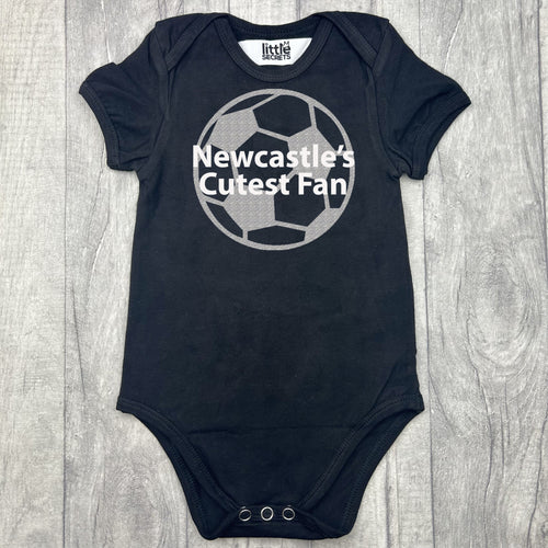 baby short sleeve black romper bodysuit, with a silver football design with white lettering over the top saying Newcastle's Cutest Fan.