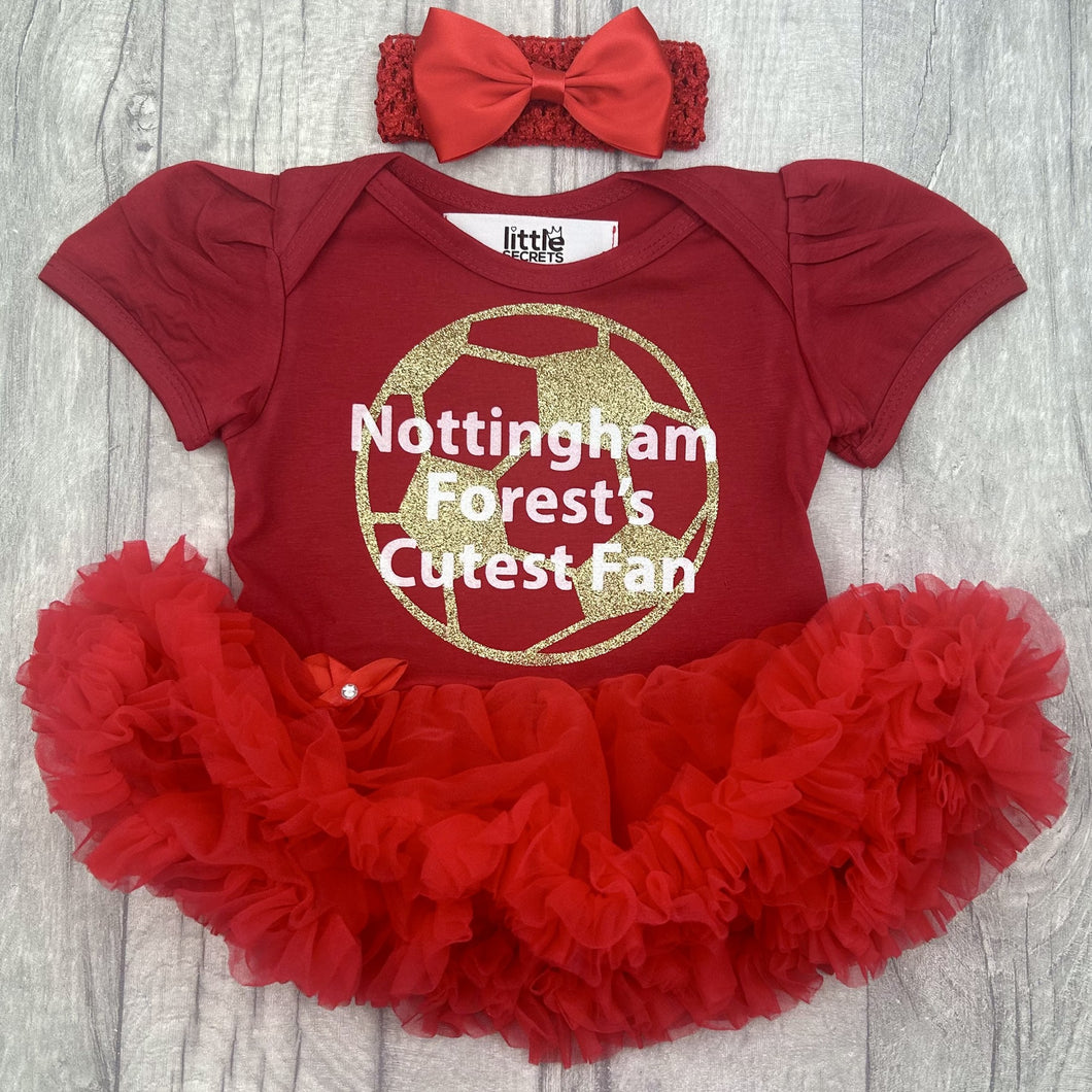 Baby girls short sleeve red tutu romper with bow headband above. The tutu romper features a gold football design with white lettering central over the top saying Nottingham Forest's Cutest Fan.