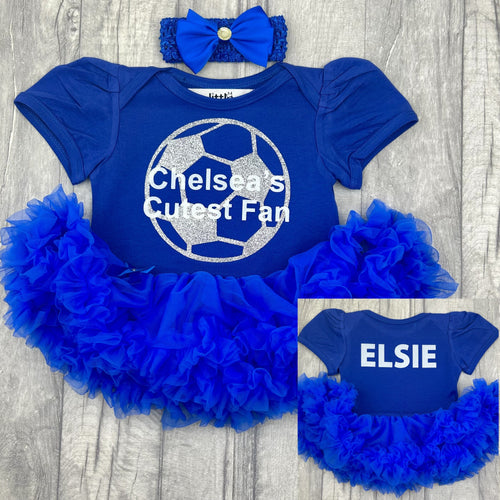 Baby girls short sleeve cotton soft royal blue tutu romper with bow headband above. The front of the tutu romper features a silver glitter football design and white text central over the top saying Chelsea's Cutest Fan. On the back for the tutu romper features personalised name.