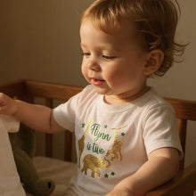 Load image into Gallery viewer, Child wearing a white shirt with gold animal graphics and text, sitting in a wooden crib.
