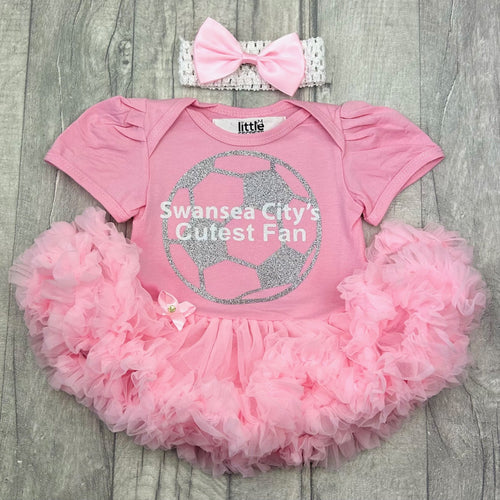 Baby girls short sleeve pink tutu romper with bow headband above. The tutu romper features a silver football design with white lettering over the top saying Swansea City's Cutest Fan.