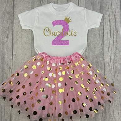 White top with pink and gold polka dot skirt. The top features light pink glitter number 2 and gold glitter crown and name.