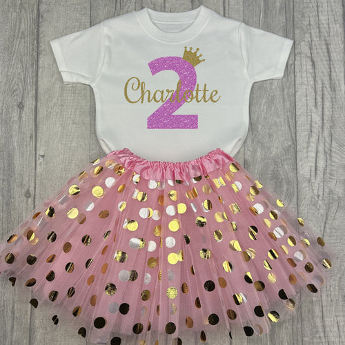 White top with pink and gold polka dot skirt. The top features light pink glitter number 2 and gold glitter crown and name.