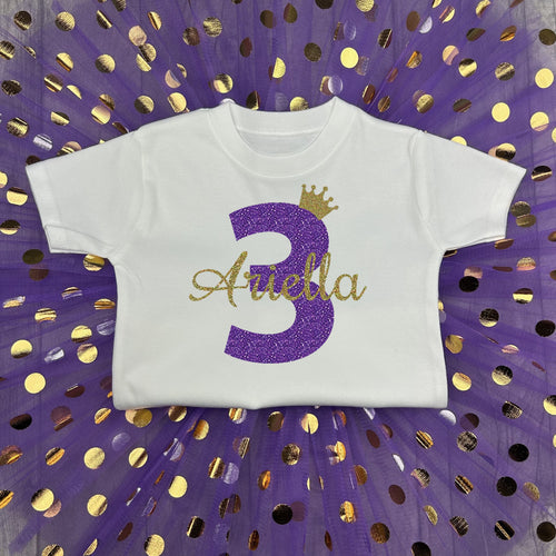 White top with purple and gold polka dot tutu skirt. The t-shirt features a purple glitter number 3 and gold glitter crown and name.