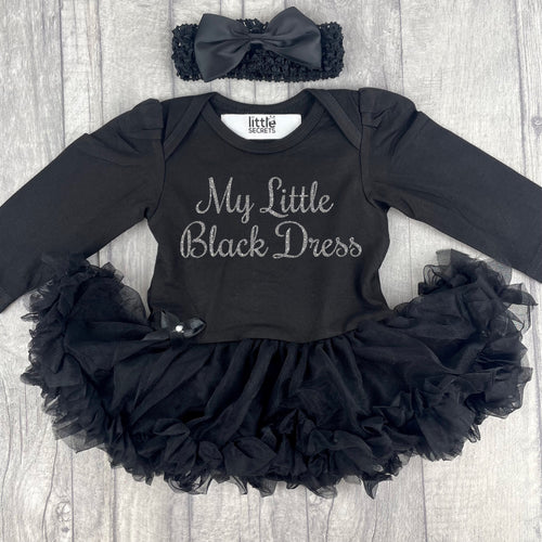 Baby Girls long sleeve black tutu romper with matching bow headband above. The tutu romper features silver glitter script text saying My Little Black Dress