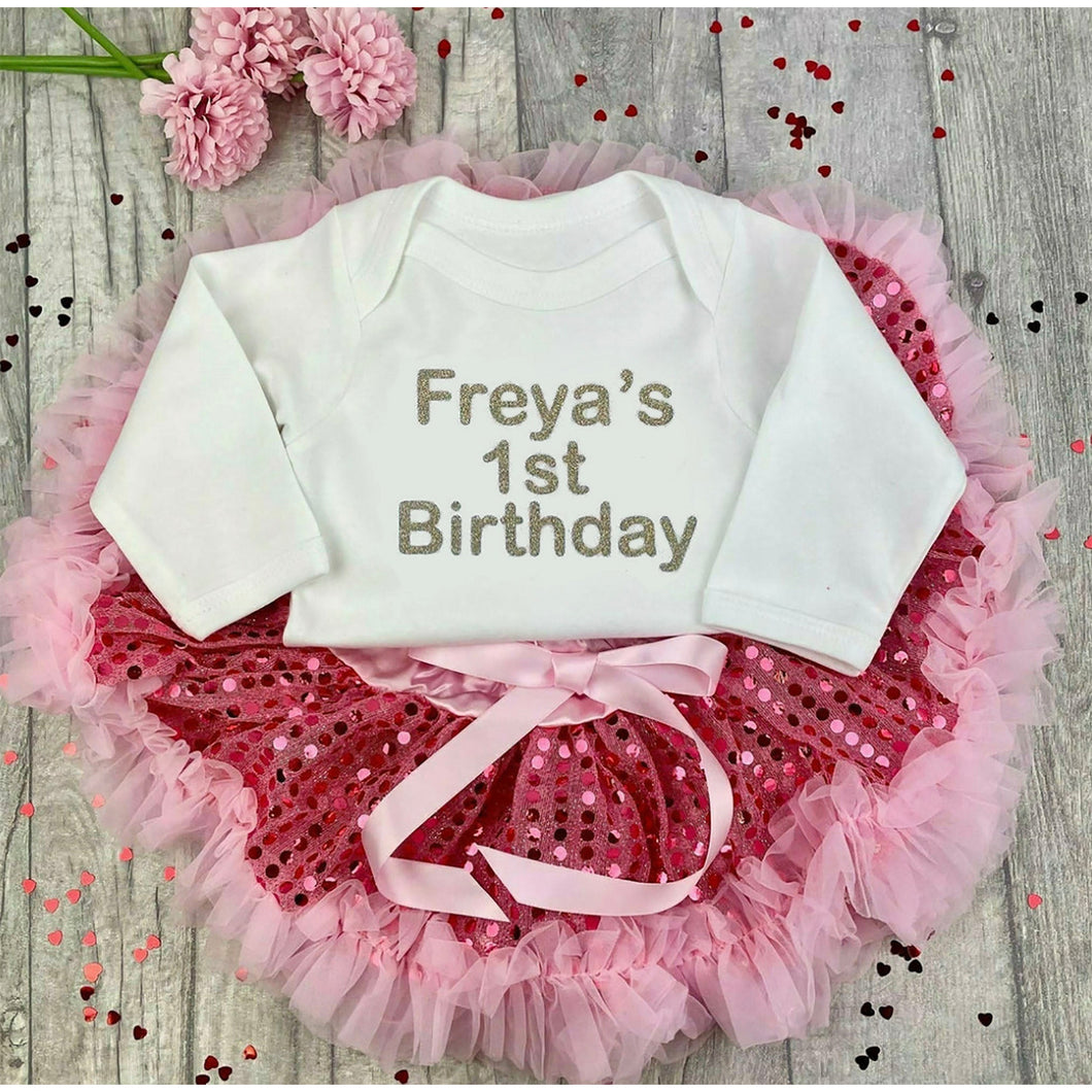 Girls 1st Birthday Sequin Outfit, Personalised White Romper with gold writing saying 1st birthday and a pink Sequin Tutu Skirt satin ribbon